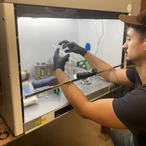 Pedro, técnico da SU Laser Brasil, em manutenção de componente ótico na bancada